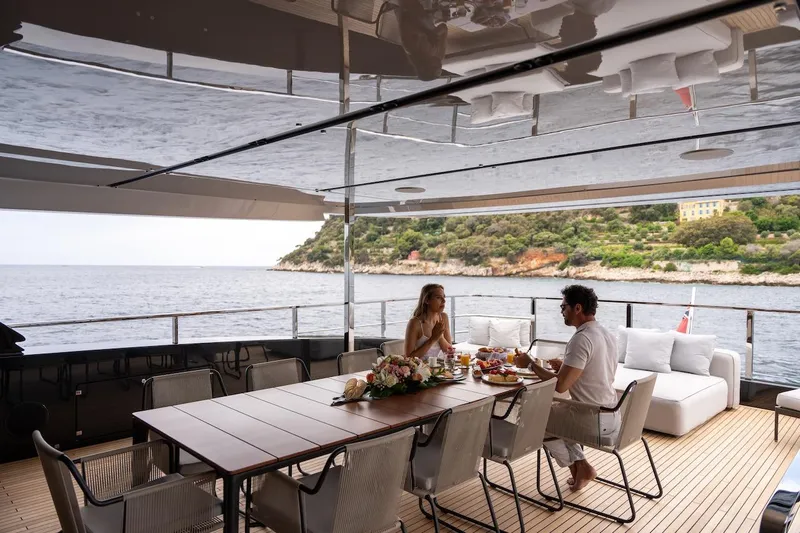 Tasty Waves Yacht Photos Pics Couple dining on luxurious 2025 Riva 130' Bellissima yacht, scenic coastal view.