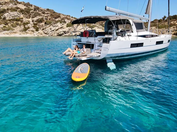 Euphoria Yacht Photos Pics 2021 Jeanneau 60 yacht anchored in clear blue water with paddleboard nearby.