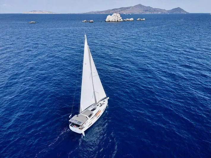 Euphoria Yacht Photos Pics Jeanneau 60 sailboat cruising in open sea, 2021 model, with distant islands in the background.
