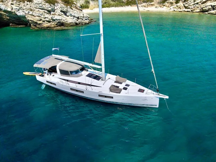Euphoria Yacht Photos Pics Jeanneau 60 yacht, 2021 model, anchored in clear turquoise waters near a rocky shoreline.