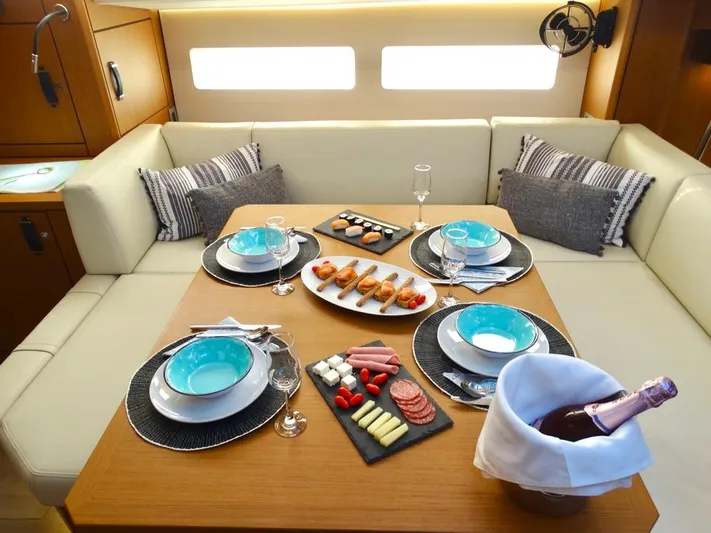 Euphoria Yacht Photos Pics Luxurious dining setup in Jeanneau 60 yacht, 2021 model, featuring elegant tableware and gourmet appetizers.