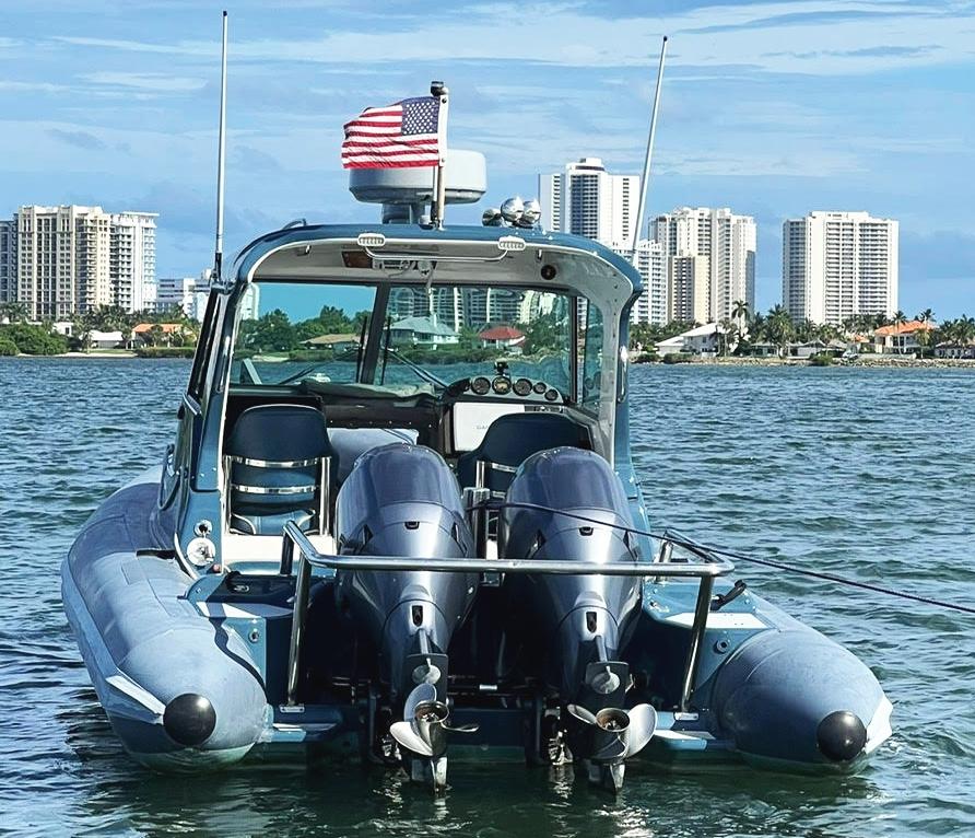 Protector Targa 28 boat on water, city skyline in background, American flag flying.