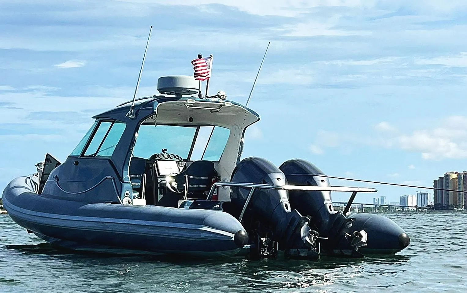 2000 Protector Targa 28 boat with dual engines on calm water, city skyline in background.
