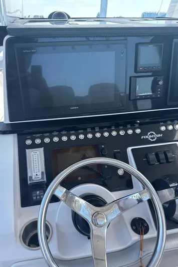  Yacht Photos Pics Control panel of a 2018 Fountain 38cc boat with steering wheel and electronic displays.