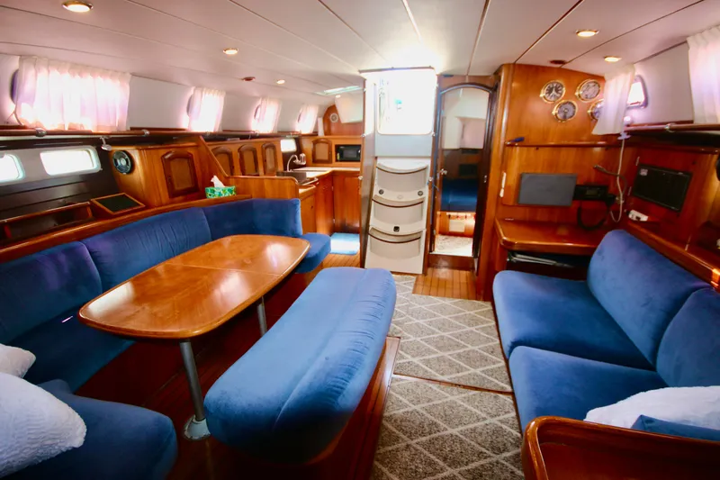 Exfil Yacht Photos Pics Interior of 1998 Beneteau Oceanis 461 yacht with blue seating and wooden finishes.