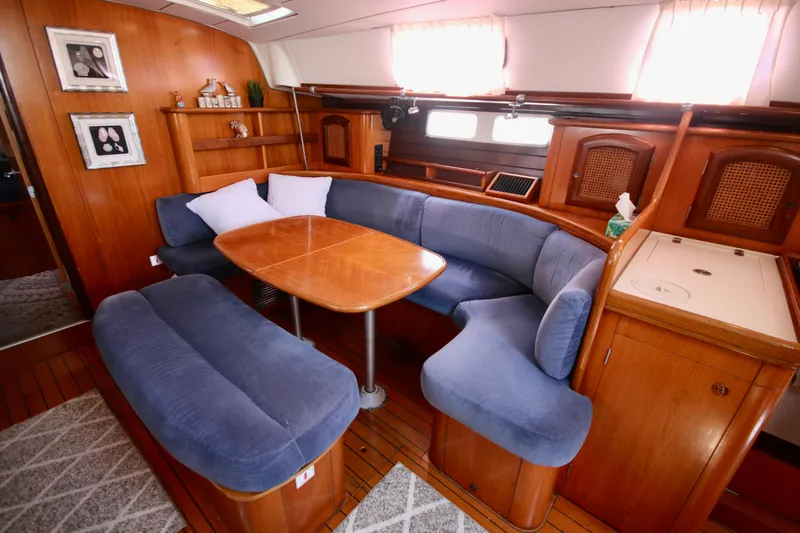 Exfil Yacht Photos Pics Interior of 1998 Beneteau Oceanis 461 yacht with blue seating and wooden table.