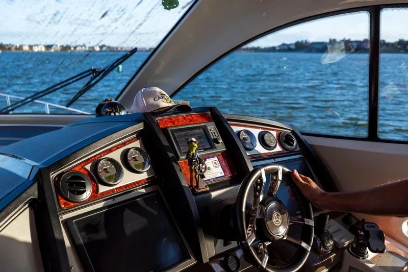 Epic Yacht Photos Pics 2013 Cruisers Yachts 540 Sports Coupe helm with gauges, steering wheel, and water view.