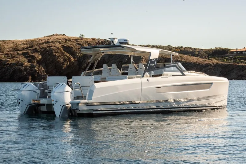  Yacht Photos Pics 2025 YOT 36 luxury yacht on calm water near rocky coastline.