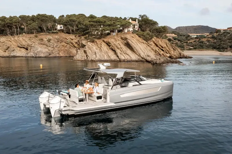  Yacht Photos Pics 2025 YOT 36 boat anchored near rocky coastline with people relaxing onboard.