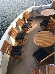 The Entertainer Yacht Photos Pics Outdoor seating area on 1984 Hatteras 61 Cockpit MY yacht with wooden chairs and tables.
