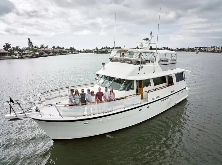 The Entertainer Yacht Photos Pics 1984 Hatteras 61 Cockpit MY yacht with people onboard, cruising on a calm waterway.