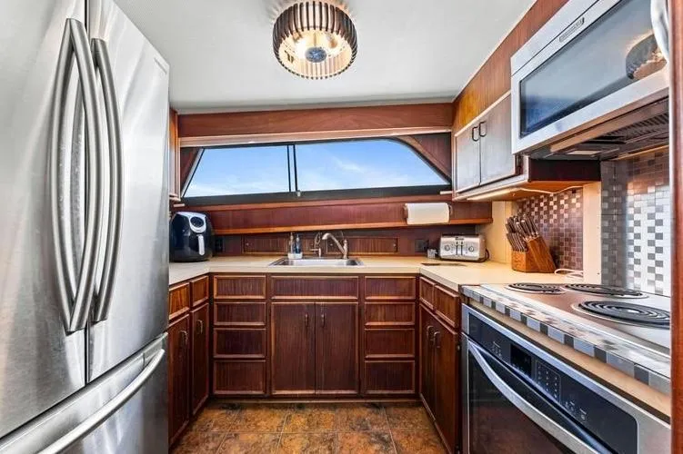 The Entertainer Yacht Photos Pics 1984 Hatteras 61 Cockpit MY kitchen with modern appliances and wood cabinetry.