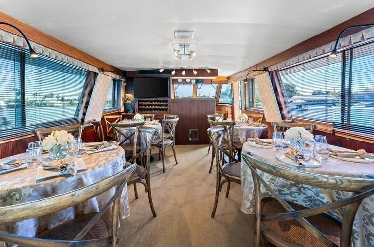 The Entertainer Yacht Photos Pics Luxurious dining area on 1984 Hatteras 61 Cockpit MY yacht, elegantly set tables, panoramic windows.