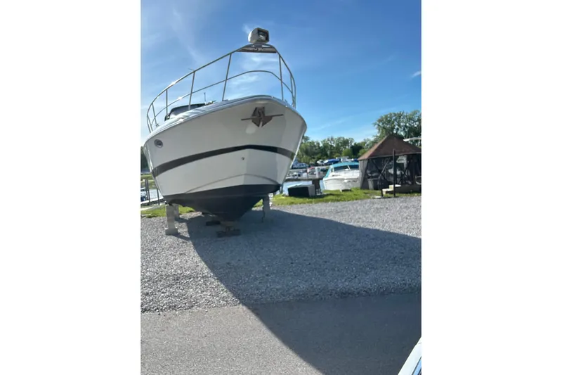  Yacht Photos Pics 2000 Cruisers 3870 boat on gravel, marina background, clear sky.