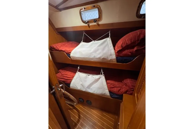 "fast Water" Yacht Photos Pics Bunk beds in 2006 Tayana Deck Salon yacht cabin with red bedding and wooden interior.