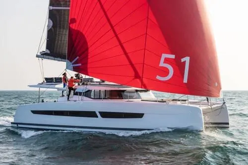 Maeva Yacht Photos Pics 2023 Fountaine Pajot Catamaran Aura 51 sailing with vibrant red sails on open water.