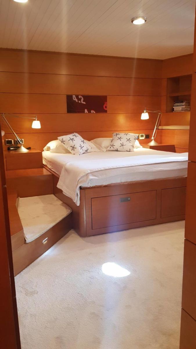 Luxurious bedroom in 2005 Explorer 70' yacht with cozy lighting and elegant wood paneling.