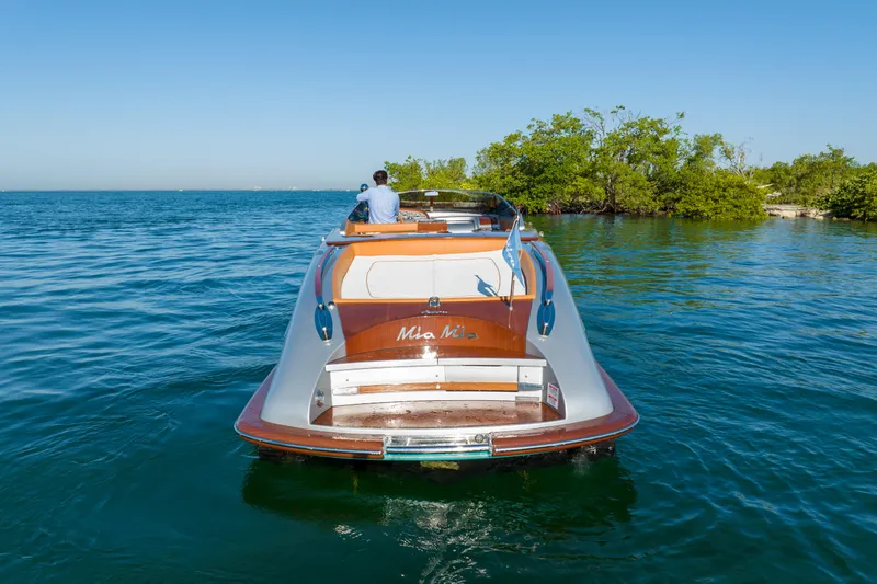 Mia Mia Yacht Photos Pics 2020 Riva Aquariva boat cruising on clear blue water near lush green trees.