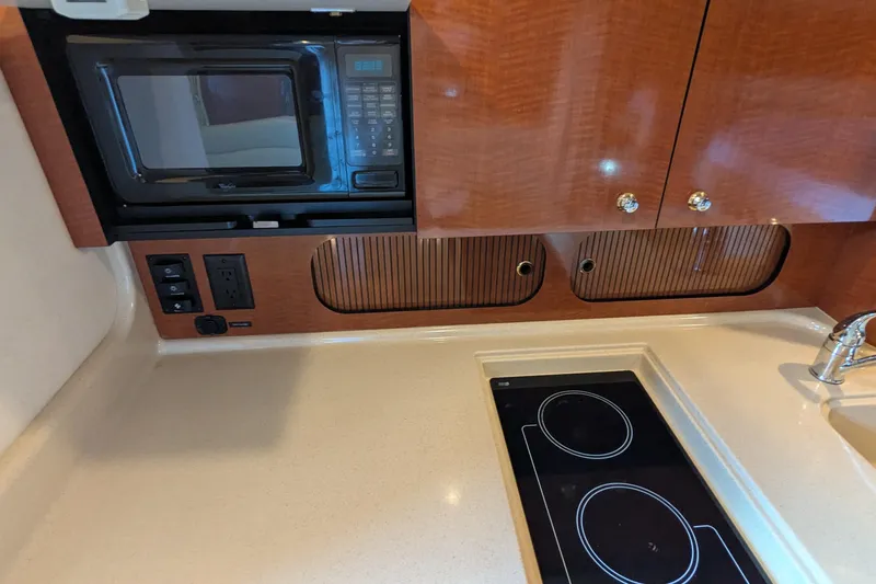  Yacht Photos Pics 2004 Sea Ray 340 Sundancer kitchen with microwave, stove, and wooden cabinets.