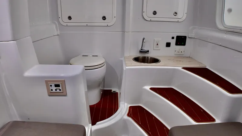  Yacht Photos Pics 2022 Yellowfin 42 Offshore boat interior with toilet, sink, and wooden steps.