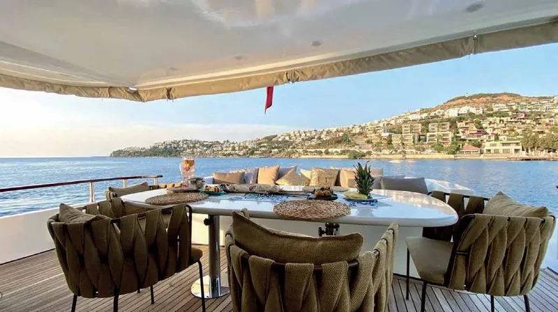 Vedo Yacht Photos Pics Luxurious Bilgin 30-meter yacht deck with elegant seating, overlooking serene coastal scenery, 2004 model.