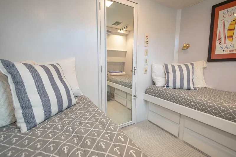  Yacht Photos Pics 1989 Hatteras Custom Cockpit cabin with twin beds, nautical decor, and striped pillows.