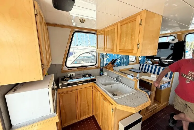  Yacht Photos Pics Cozy kitchen area in 2000 LEBLANC Leo 38 boat with wooden cabinets and dining nook.