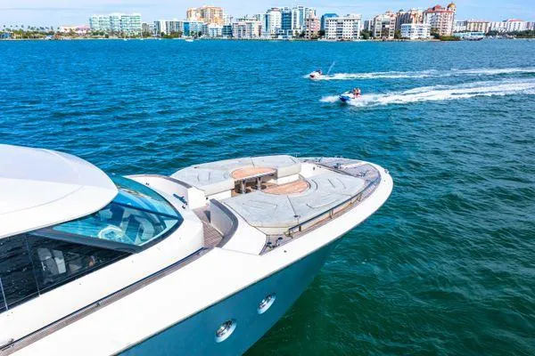 Yacht Photos Pics Monte Carlo Yachts MCY 70 cruising on blue waters, city skyline in background, 2018 model.