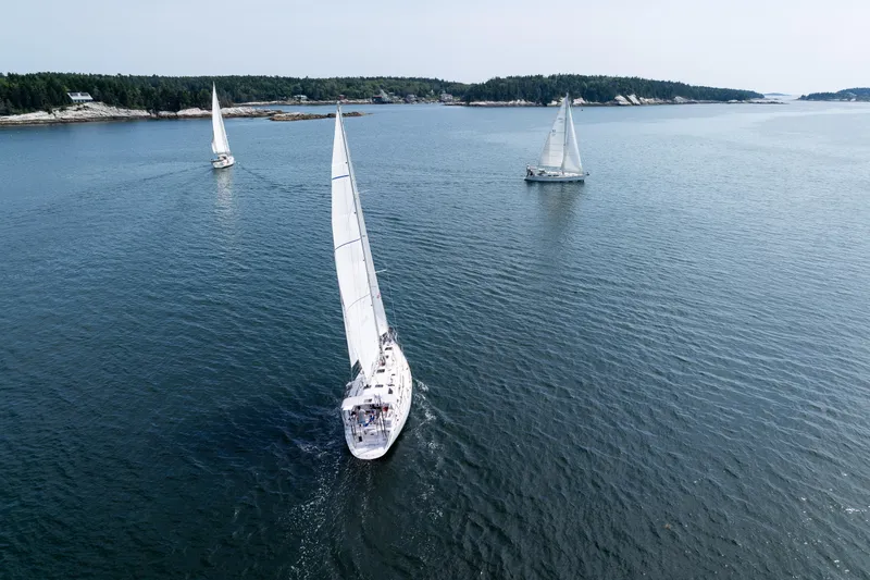 Boojum Yacht Photos Pics Sailboats on open water, featuring a 2024 Outbound 46 model, near a forested coastline.