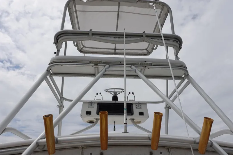  Yacht Photos Pics 1997 Pursuit 3400 Offshore boat tower with fishing rod holders against cloudy sky.