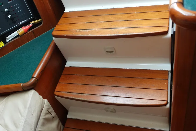  Yacht Photos Pics Wooden steps inside a 1997 Pursuit 3400 Offshore boat, featuring a control panel and green carpet.