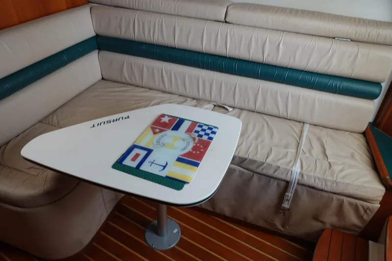  Yacht Photos Pics Interior of 1997 Pursuit 3400 Offshore boat with cushioned seating and nautical-themed table.