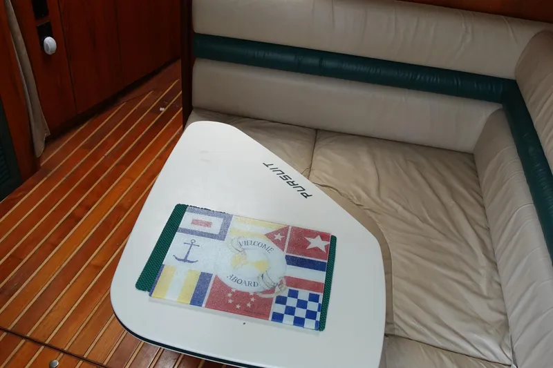  Yacht Photos Pics Interior of 1997 Pursuit 3400 Offshore boat with cushioned seating and nautical-themed mat.