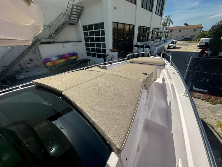  Yacht Photos Pics 2024 Axopar 37XC CROSS CABIN with sunbathing deck, docked near a modern building.