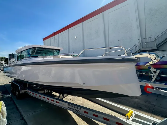  Yacht Photos Pics 2024 Axopar 37XC CROSS CABIN boat on trailer, parked outdoors under clear sky.