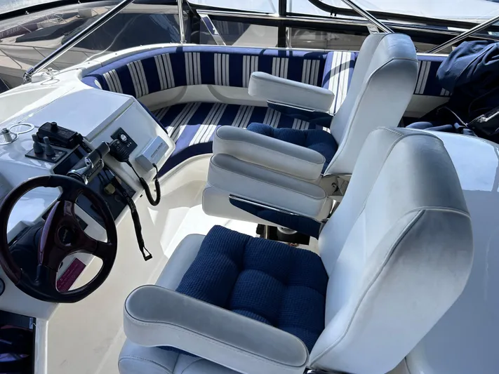 Just Chillin Yacht Photos Pics 2006 Viking Princess 61 Flybridge helm with striped seating and steering wheel.
