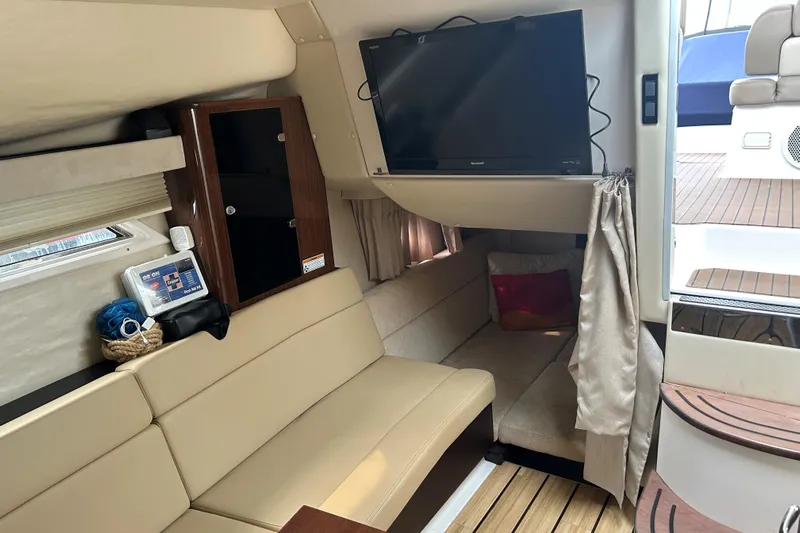 Sound Decision Yacht Photos Pics Interior of 2013 Regal 35 Sport Coupe with beige seating, TV, and wooden accents.