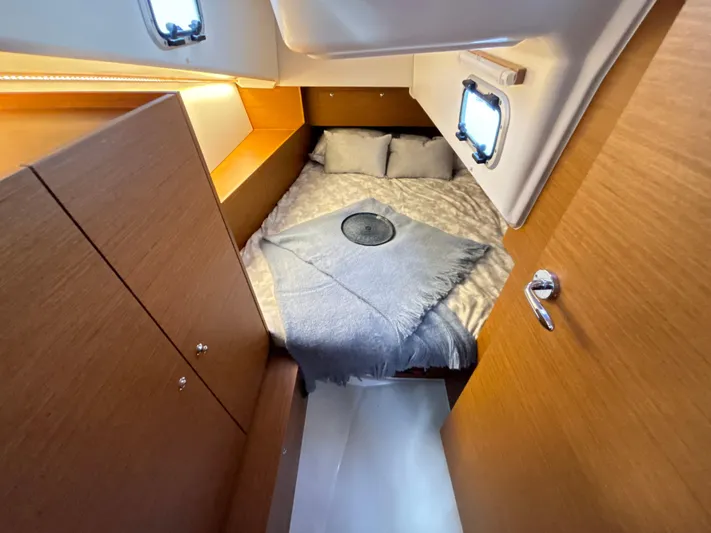  Yacht Photos Pics 2024 Jeanneau Sun Odyssey 350 cabin interior with cozy bed and wooden finish.