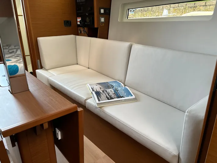 Yacht Photos Pics 2024 Jeanneau Sun Odyssey 350 interior with white sofa and open magazine.