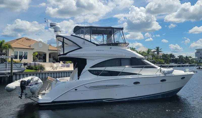 'perrydise' Yacht Photos Pics 2007 Meridian 341 Sedan yacht docked by waterfront homes under a blue sky.
