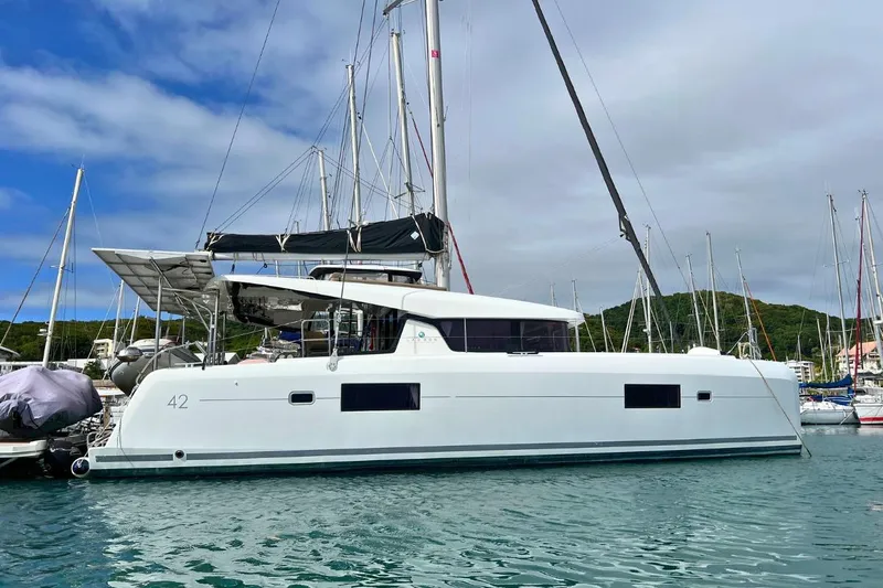 Mocean Yacht Photos Pics 2017 Lagoon 42 catamaran docked in marina, surrounded by sailboats and calm water.
