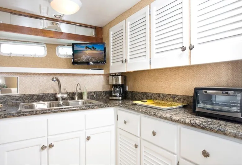 Savoy Yacht Photos Pics 1970 Chris-Craft Commander kitchen with granite countertops, white cabinets, and modern appliances.