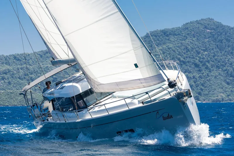  Yacht Photos Pics Sailing yacht Moody 48DS 2026 navigating blue waters near lush green hills.