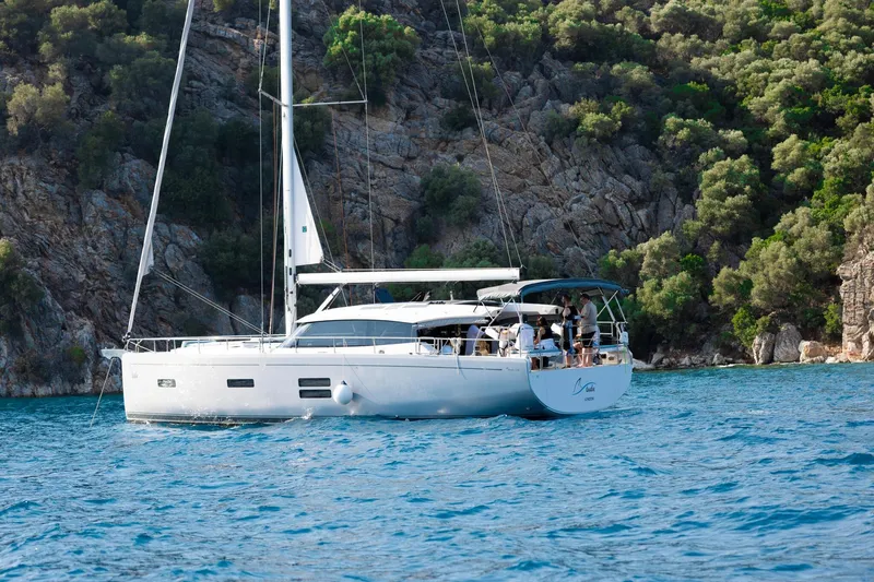  Yacht Photos Pics Sailing yacht Moody 48DS 2026 cruising near rocky coastline with lush greenery.