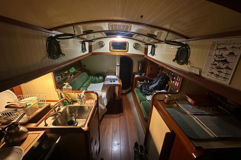 Solimar Yacht Photos Pics Cozy interior of a 2000 Sam L. Morse Bristol Channel Cutter 28 sailboat, featuring a compact kitchen and seating area.