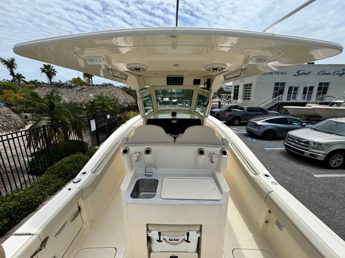  Yacht Photos Pics 2025 Scout 305 LXF boat interior with helm, sink, and storage, parked at a marina.