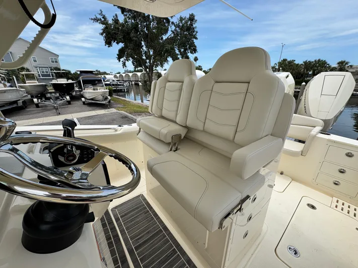  Yacht Photos Pics 2025 Scout 305 LXF boat interior with luxurious seating and steering wheel, dockside view.