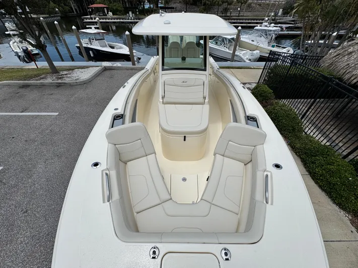 Yacht Photos Pics 2025 Scout 305 LXF boat with spacious seating, docked near a marina.