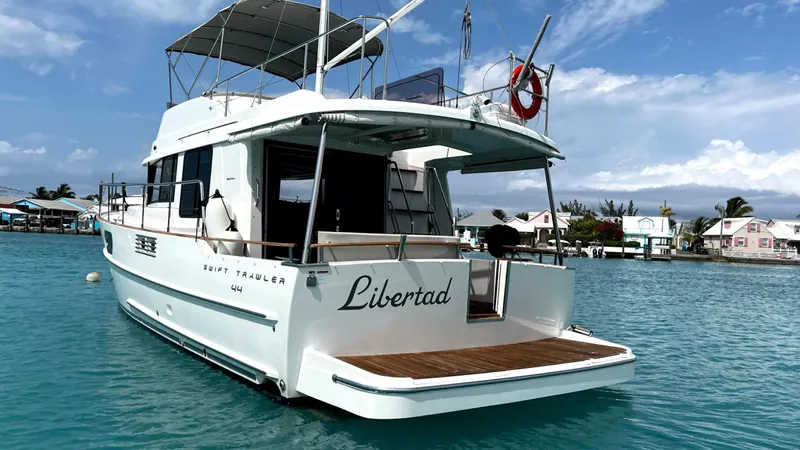Libertad Yacht Photos Pics 2020 Beneteau Swift Trawler 44 on water, rear view, clear sky, docked nearby.