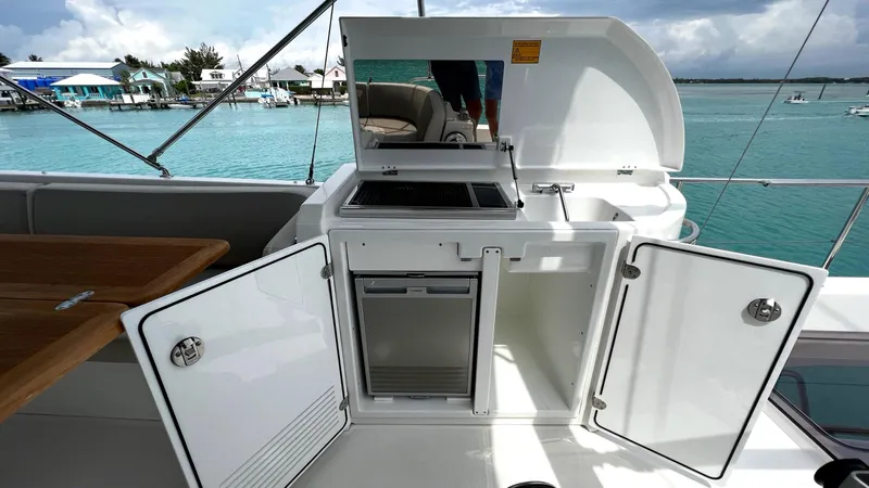 Libertad Yacht Photos Pics Outdoor kitchenette on 2020 Beneteau Swift Trawler 44, featuring storage and grill, near turquoise waters.